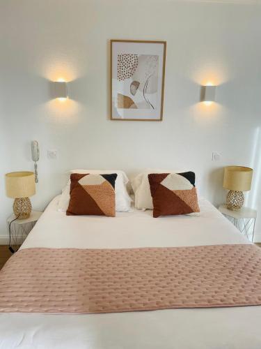a bedroom with a white bed with two lamps at Hôtel Porte Mars Reims Gare Centre Arena in Reims