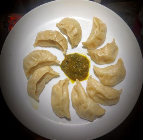 a white plate of dumplings with sauce on it at The Silver Spring Homestay in Darjeeling