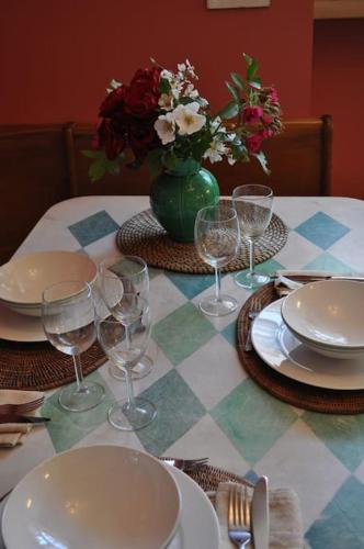 a table with plates and glasses and a vase with flowers at Moulin de Merzé in Cortambert