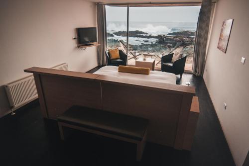 a room with a bed and a large window at Hotel 8 al Mar in Pichilemu