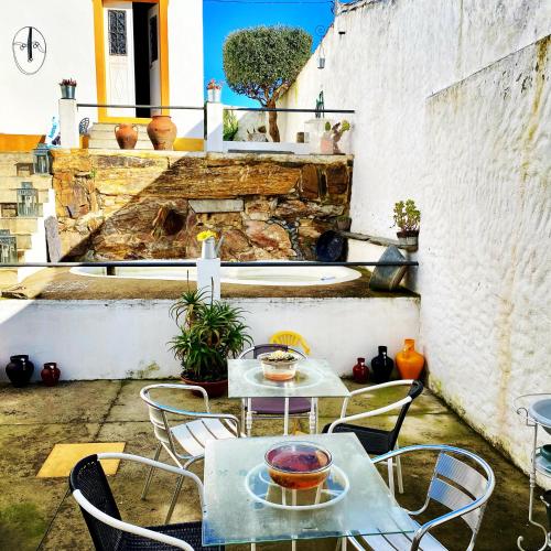 a patio with two tables and chairs and a wall at Os 5 Sentidos in Mourão