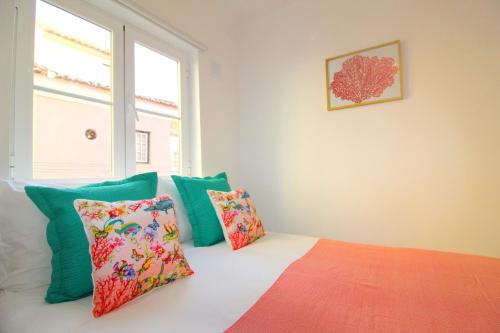 Habitación con cama con almohadas coloridas y ventana. en Apartments Center Alfama II, en Lisboa