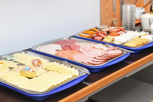two trays filled with different types of meats and cheese at Hotel-Pension Janssen - Gästehaus Huus an't Deep in Neuharlingersiel