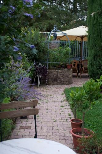 a garden with a bench and plants and an umbrella at Moulin de Merzé in Cortambert
