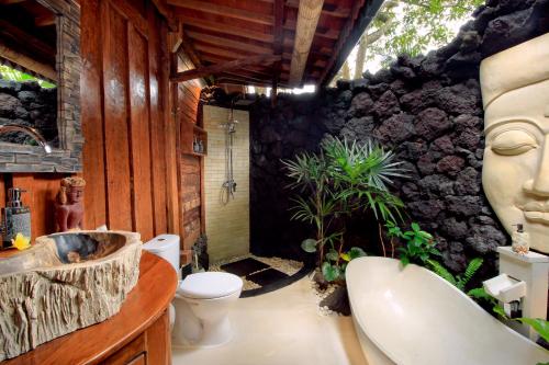 a bathroom with a stone wall with a sink and a toilet at Masakali Retreat in Ubud