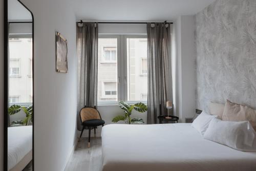 a bedroom with a white bed and a window at Apartamentos Progres in Hospitalet de Llobregat