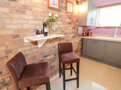 una cocina con 2 sillas y una pared de ladrillo en Ground floor flat, en Llandudno