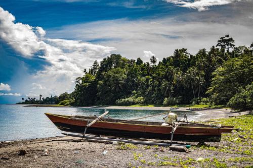 a boat sitting on the shore of a beach at Sanctum Una Una Eco Dive Resort in Pulau Unauna