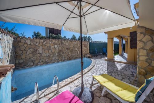 a patio with an umbrella and chairs and a pool at Villa Tiziana&Alessia in Castiadas