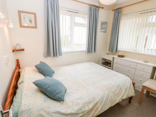 a bedroom with a bed and two windows at Buddleia Cottage in Seaview