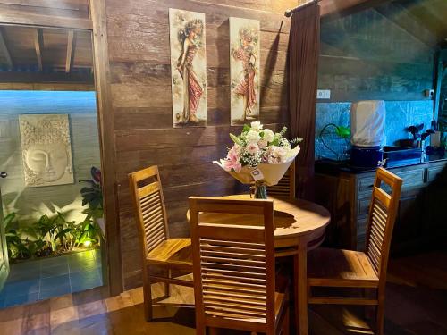 a dining room table and chairs with a vase of flowers at Masakali Retreat in Ubud