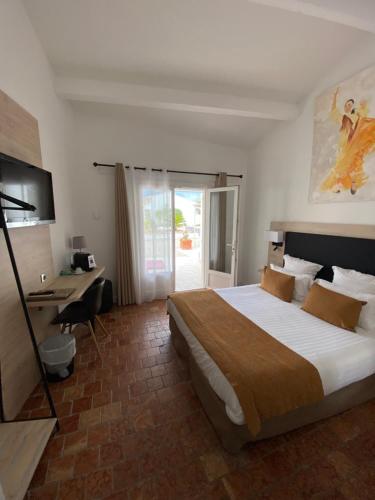 a hotel room with a large bed and a desk at Le Mas de Cocagne in Saintes-Maries-de-la-Mer