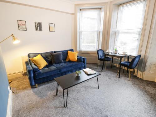 a living room with a blue couch and a table at Sapphire Suite in Barmouth