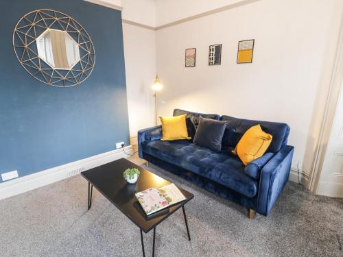 a living room with a blue couch and a table at Sapphire Suite in Barmouth