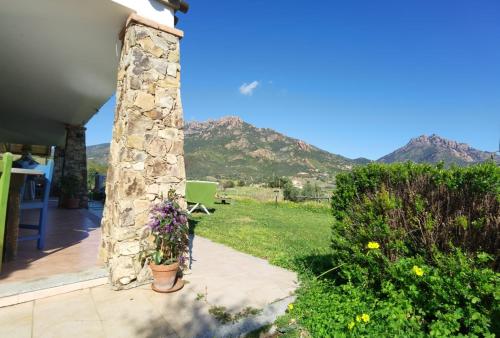 a house with a stone pillar with mountains in the background at Domu abi manna in Tertenìa
