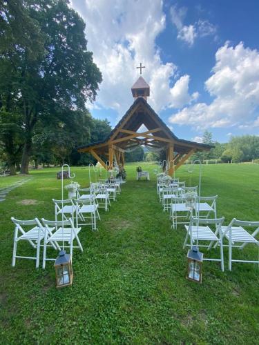 a group of white chairs in front of a gazebo at Penzion a Restaurace Bělecký Mlýn in Ptení