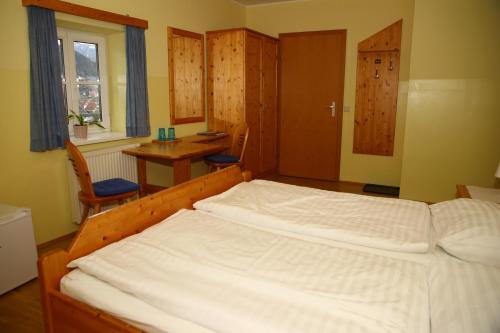 ein Schlafzimmer mit einem großen weißen Bett und einem Tisch in der Unterkunft Pernegger Dorfstub´n in Pernegg an der Mur