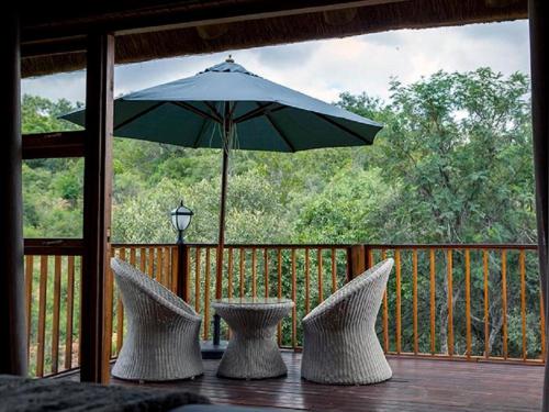 a patio with two chairs and an umbrella on a deck at Lichenry Bush Lodge in Mokopane
