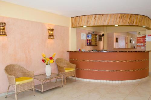a waiting room with chairs and a counter with a vase of flowers at Hotel Palmanova in Maceió