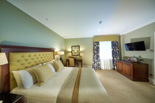 a hotel room with a large bed and a television at Golf View Hotel & Spa in Nairn