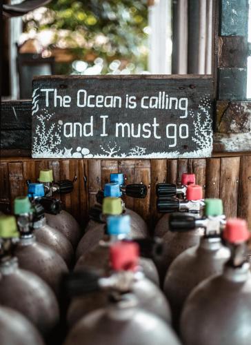 a bunch of bottles with a sign that says the ocean is calling and i must at Sanctum Una Una Eco Dive Resort in Pulau Unauna