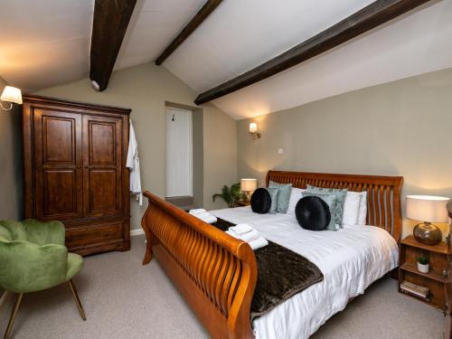 een slaapkamer met een groot bed en een groene stoel bij Pemba Cottage in Skipton