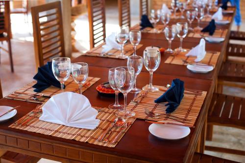 Una larga mesa de madera con copas de vino y servilletas. en Karunakarala Ayurveda Resort, en Wayikkal