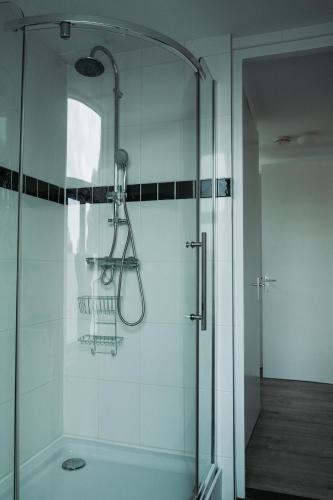 a shower with a glass door in a bathroom at Bed and Breakfast du Parc in Zaandam