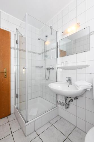 a bathroom with a glass shower and a sink at Hotel-Pension Janssen - Gästehaus Huus an't Deep in Neuharlingersiel