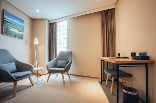 a room with two chairs and a table and a desk at Mega Hotel in Chiayi City