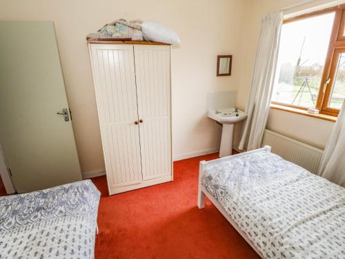 a bedroom with two beds and a cabinet and a window at Errisbeg in Clifden