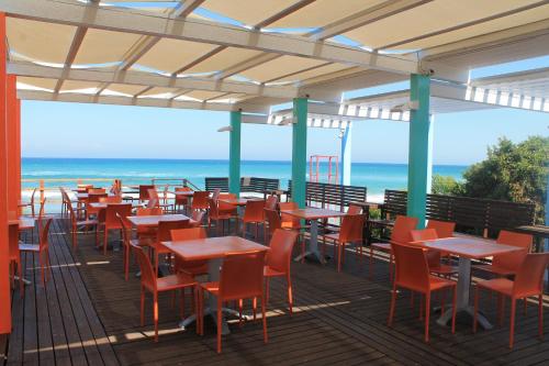 een rij tafels en stoelen op een terras met het strand bij Serra Degli Alimini 2 in Alimini