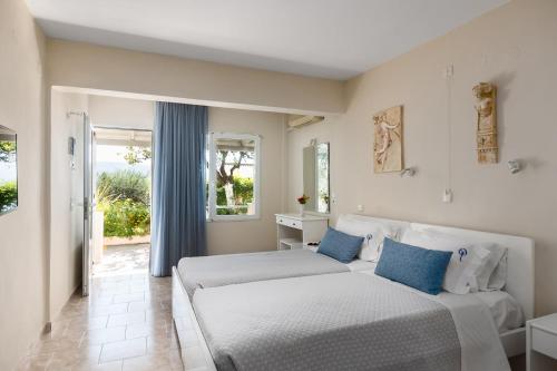 two beds in a room with a window at Odysseus Hotel in Paleokastritsa