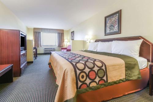 a hotel room with a bed and a flat screen tv at Super 8 by Wyndham Burleson Fort Worth Area in Burleson