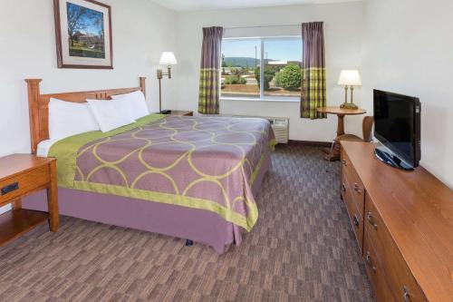 a hotel room with a bed and a flat screen tv at Super 8 by Wyndham Central Pt Medford in Central Point