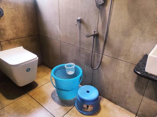 a bathroom with a shower and a toilet and a bucket at Hotel Manasi Royal in Satara