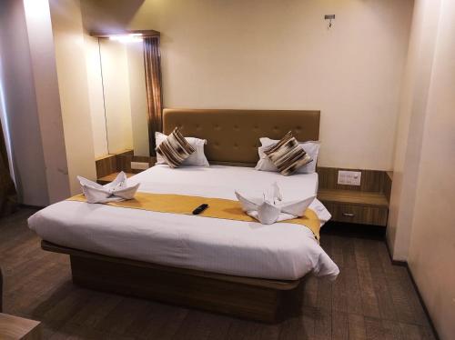 a bedroom with a large bed with white sheets and pillows at Hotel Manasi Royal in Satara