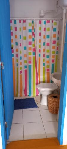 a bathroom with a toilet and a colorful shower curtain at Casinha do Bem-Viver na Vila de Itaúnas in Itaúnas