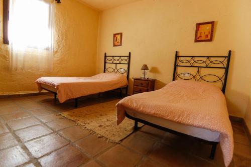 a bedroom with two beds and a window at Casas Rurales El Viejo Castaño 1 in Pujerra