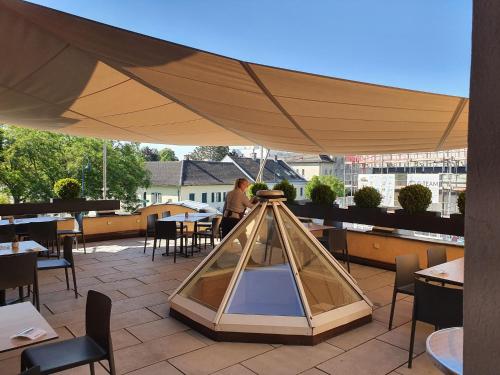 ein großer Sonnenschirm auf einer Terrasse mit Tischen und Stühlen in der Unterkunft Pension Müller Gartner in Groß-Enzersdorf