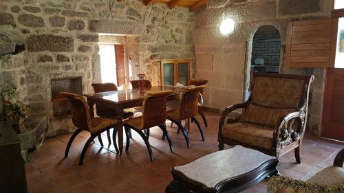 comedor con mesa, sillas y pared de piedra en O POMAR VELLO, en Pontevedra