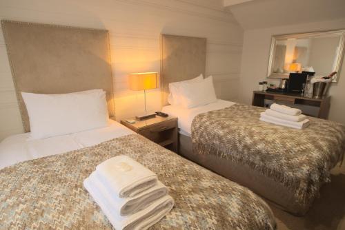 Habitación de hotel con 2 camas y toallas. en McCafferty's Guesthouse Ilford, en Ilford
