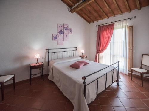 a bedroom with a bed and two chairs and a window at Il Convento di Monte Pozzali in Massa Marittima