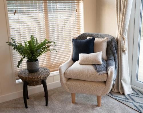 a chair with pillows and a plant in a room at Hollicarrs - The Rushes in Riccall