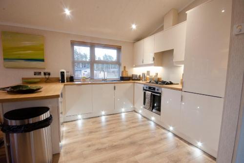 a kitchen with white cabinets and a wooden floor at Hollicarrs - The Rushes in Riccall