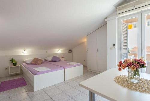 a white bedroom with a large bed and a table at Apartments Niko in Novalja