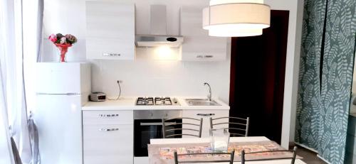uma pequena cozinha branca com uma mesa e um lavatório em Pina's tao sea home em Taormina