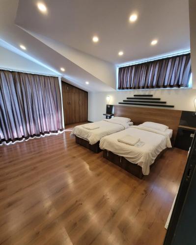 two beds in a room with wooden floors and curtains at BEGONVİL VİLLA in Belek