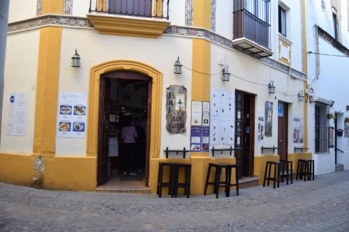 een geel en wit gebouw met tafels en stoelen buiten bij Pensión San Marcos in Arcos de la Frontera