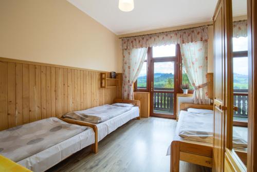 a bedroom with two beds and a large window at Schronisko PTTK Trzy Korony in Sromowce Niżne